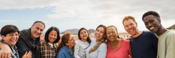 Group of multigenerational friends smiling in front of camera - Multiracial friends of different ages having fun together - Main focus on center people faces
